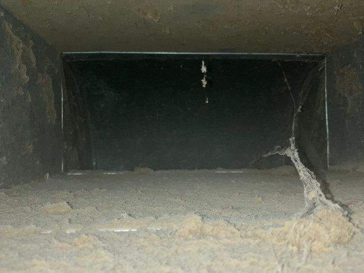 Inside ductwork before being cleaned. There is an obvious layer of dirt, dust, and debris formed around the entire inside perimeter of the ductwork.