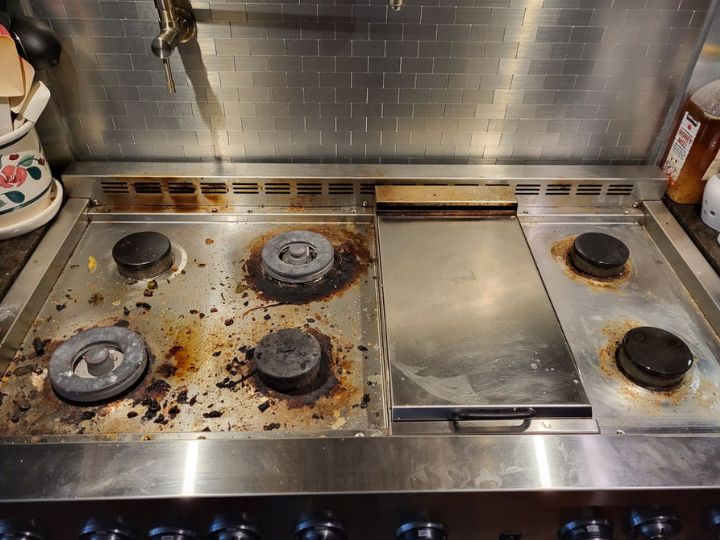 Residential stainless steel gas cooktop before being cleaned. Dull, dirt covered, caked-on dirt and grease.