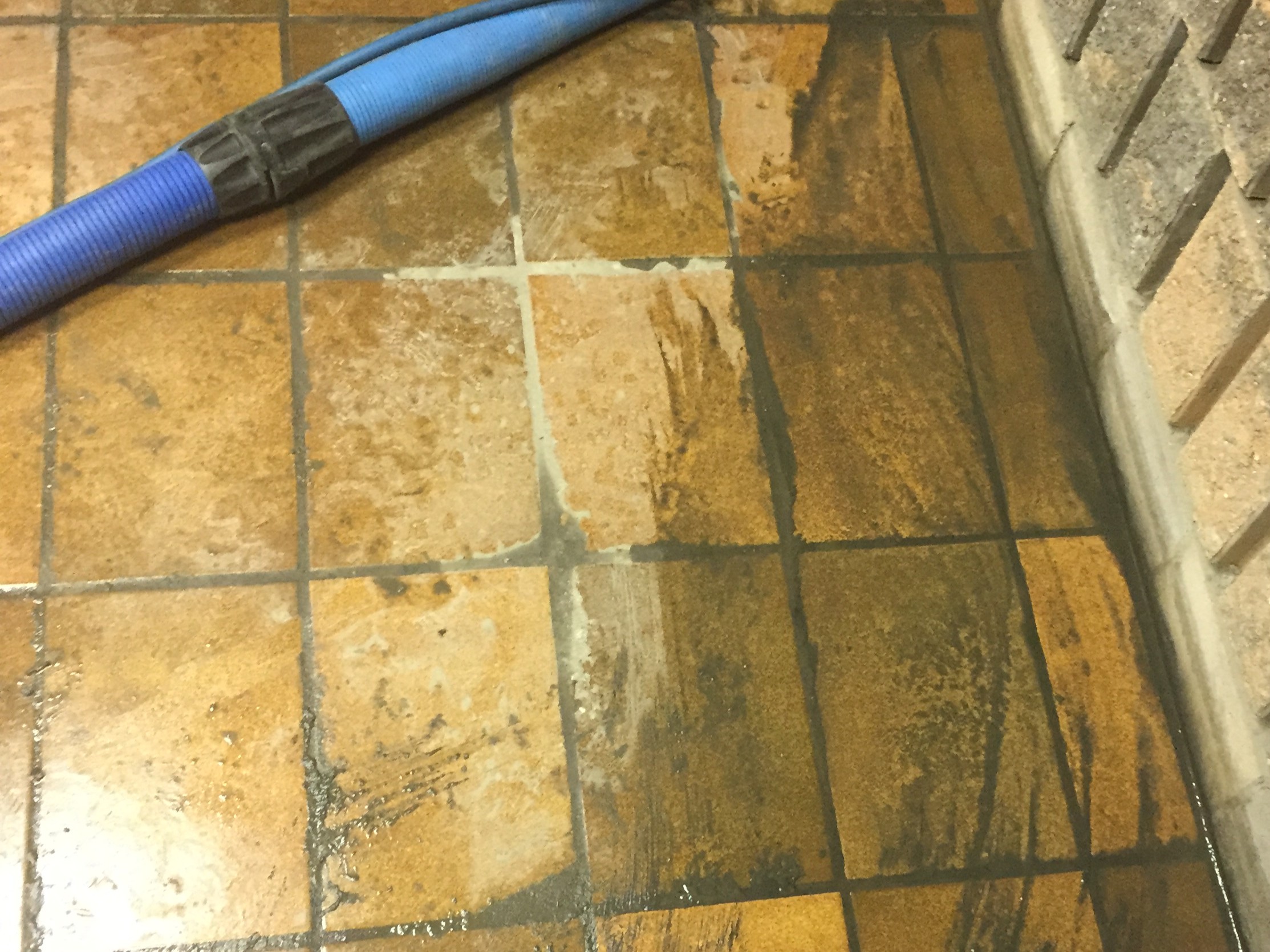Brown tile floor before cleaning, dirt covered and stained